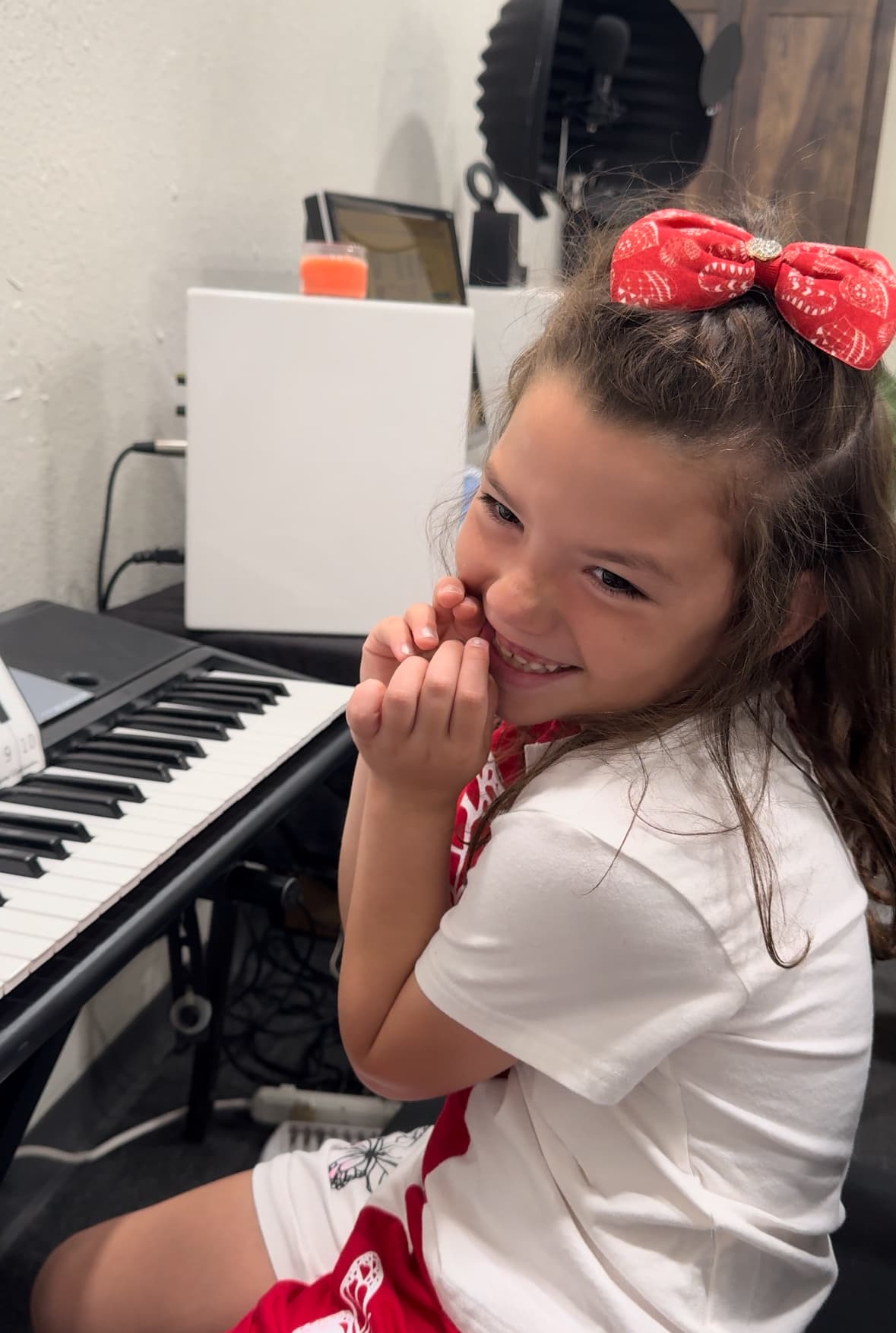 Young METLC student smiling beside a keyboard during a piano lesson.