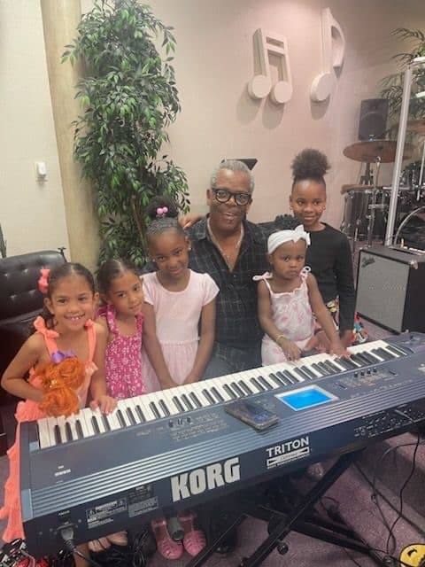 KC Cousin with young METLC students gathered behind a keyboard.