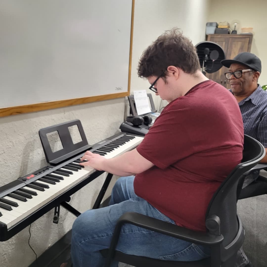 METLC student playing keyboard while KC coaches from nearby.