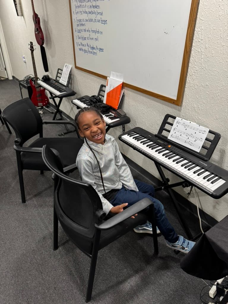Smiling METLC student seated at a keyboard lesson station.