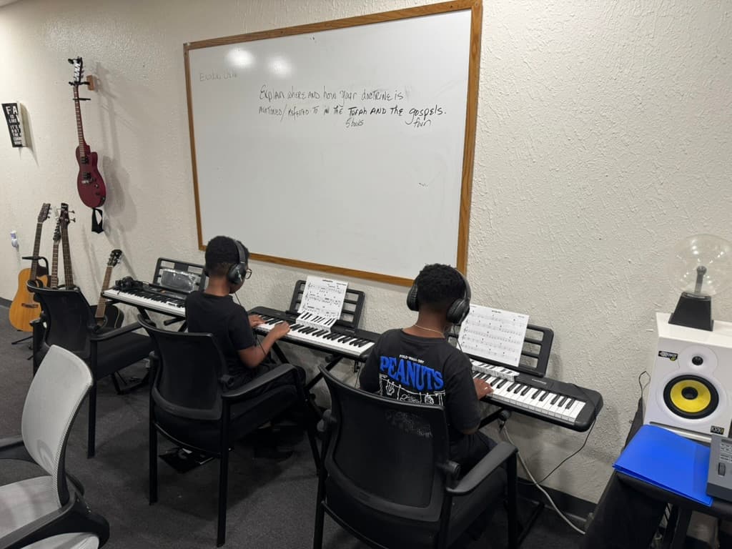 Two METLC students practicing keyboards with headphones.